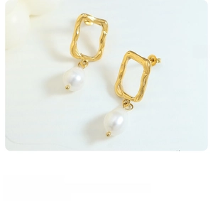 Detail of gold irregular textured metal stud with an elegant white baroque pearl drop