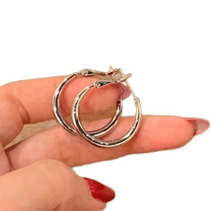 Minimalist silver hoop earrings for women held by hand to show compact size