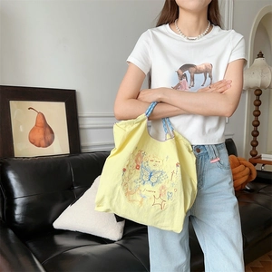 Détail du sac cabas jaune en tissu oxford avec broderie papillon et anses bleues