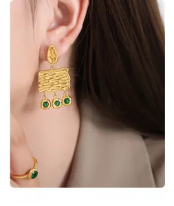Detail of vintage gold-plated rectangular earrings with green zircon tassels on a model