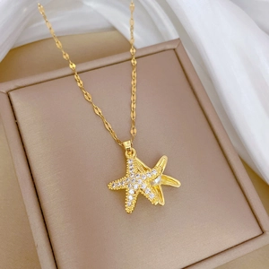 Golden starfish pearl necklace with sparkling crystals on elegant white silk background