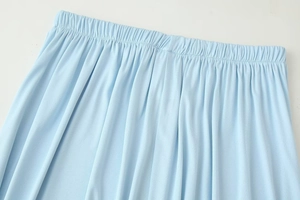 Close-up of elastic waistband on light blue high-waisted skirt with soft knit texture