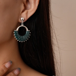 Detail shot of a dark green woven hoop earring with vintage gold metallic accents