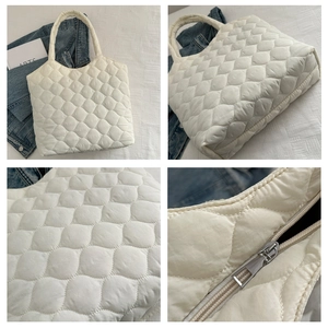 Detail view of white quilted tote bag featuring soft rhombus texture and zipper closure