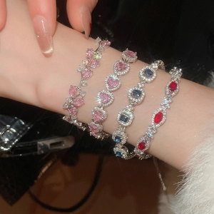 Close-up of sparkling heart and geometric zircon bracelets on a wrist with silver finish