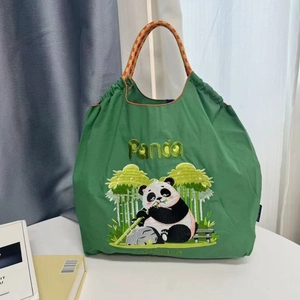 Close-up of green nylon tote bag featuring detailed panda embroidery and braided handle