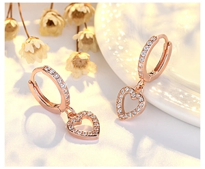 Close-up of rose gold heart hoop earrings with pave-set sparkling crystals on white surface
