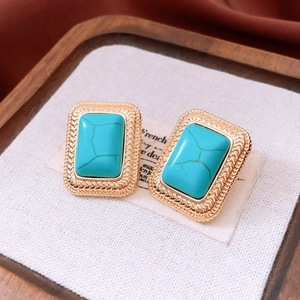 Detailed shot of retro gold square earrings with turquoise stone and woven metal edges
