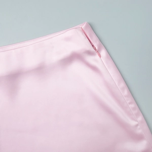 Detailed close-up of invisible zipper and silk-like satin fabric on pink mini skirt