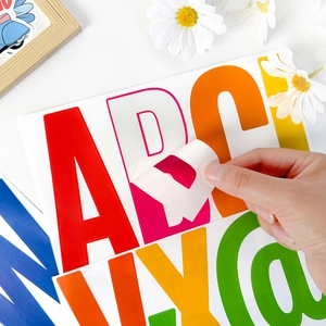Hand peeling a large colorful letter B sticker for birthday party or home decor