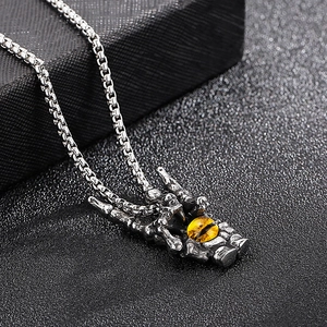 Macro shot of silver dragon claw pendant holding a yellow cat eye stone on black texture