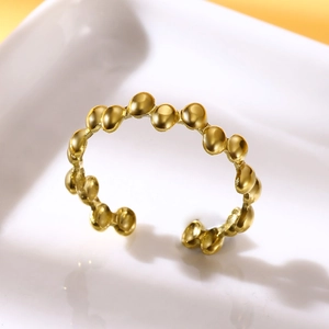 Close-up of gold beaded stainless steel adjustable open ring on white ceramic plate