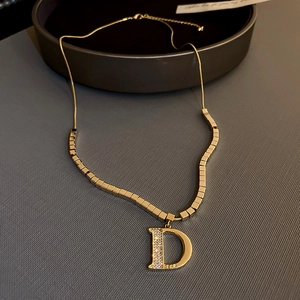 Gros plan du collier lettre D doré avec pavé de zircons et gravure DEAR sur le côté