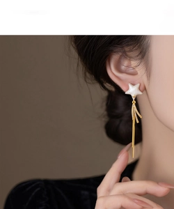 Detailed view of dangling star earrings with tassel chains on model for elegant style