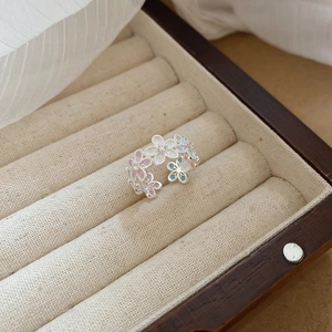 Detailed close-up of a silver flower ring with pink and blue petals in a jewelry box