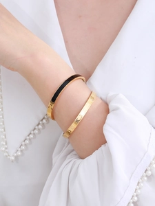 Detail of gold-plated stainless steel bangles with Roman numerals and black enamel inlay