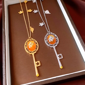 Detail of vintage key pendants in gold and silver finish with orange resin inlays