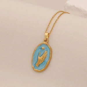 Macro shot of a gold sun flower necklace with blue heart and hand relief pendant