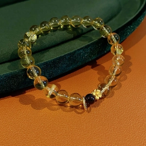 Close-up of citrine beaded bracelet with garnet accent and a golden floral charm