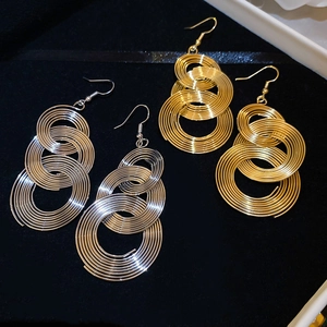 Detail view of gold and silver triple spiral wire drop earrings on black background