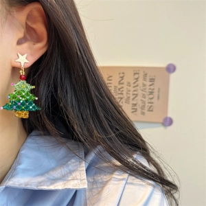Close-up of handmade beaded Christmas tree earrings with star charm on model