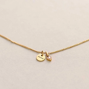 Macro shot of gold-plated necklace with custom Anna engraving and pink heart gemstone