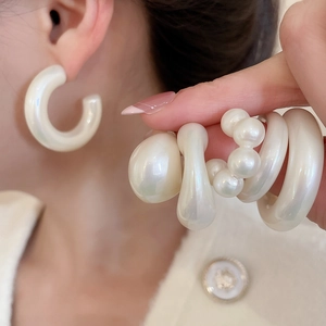 Detail of cream white acrylic earrings with a pearlescent finish in diverse geometric shapes