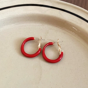 Detailed macro view of red enamel geometric C-shaped hoop earrings with gold-toned posts
