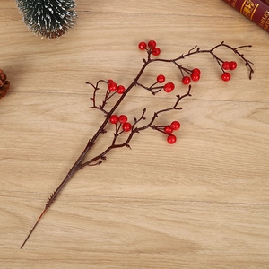 Artificial red berry branch on light wood floor for Christmas and holiday home decoration