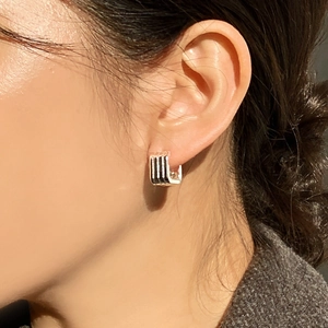 Detail of a minimalist 925 silver hoop earring with vertical stripes on female ear