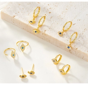 Macro detail of gold evil eye earring set with blue stones on a stone display