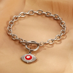 Detail of red Evil Eye charm on a silver chain bracelet with a toggle clasp design