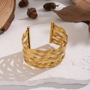 Exaggerated gold hollow mesh cuff bracelet in stainless steel on a textured white stone