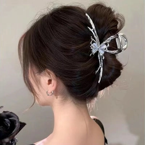 Detail of silver butterfly hair claw clip with cat eye stone on an elegant hairstyle