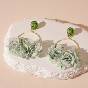 Detail of floral fabric flower earrings on textured stone base in soft natural lighting