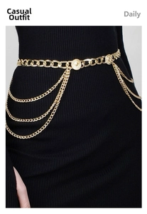 Close-up of elegant gold multi-layered chain belt with metallic charms on a black dress