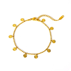 Détail de la chevillère dorée à billes avec pendentifs ronds texturés et fermoir