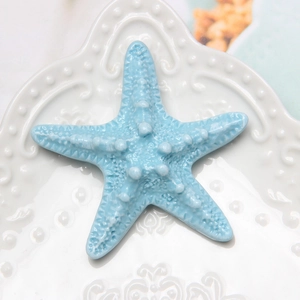 Detailed close-up of a blue resin starfish accessory on an embossed white plate