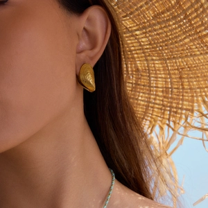 Boucles d'oreilles coquillage plaquées or 18K sur modèle avec fond de vacances d'été