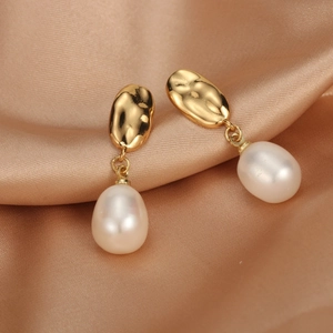 Detail of 18K gold-plated earrings with drop-shaped freshwater pearls on satin background