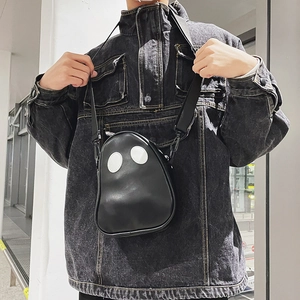 Detail of a funny ghost-shaped black PU crossbody bag worn with a casual denim jacket