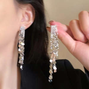 Detail von silbernen langen Quastenohrringen mit glitzernden Blattakzenten am Model