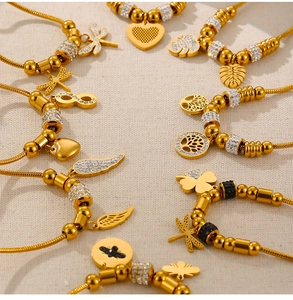 Detailed view of gold snake chain bracelets featuring sparkling rhinestone charms and symbols