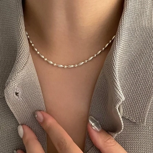 Detail of S925 sterling silver beaded necklace with olive-shaped links on model