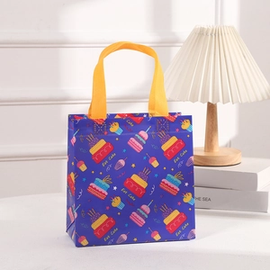 Blue non-woven gift bag with yellow handles featuring colorful cake patterns for parties