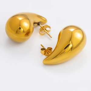 Macro shot of gold teardrop earrings with high-polish finish and sleek mirror texture
