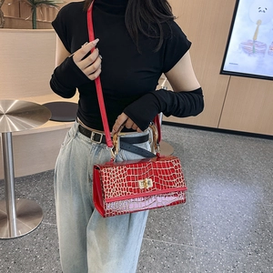 Detail of red crocodile texture handbag with bamboo handle and adjustable shoulder strap