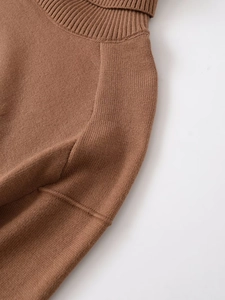 Detailed close-up of brown knit sweater featuring standing collar and ribbed shoulder stitching