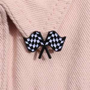 Macro shot of a checkered racing flag enamel pin displayed on pink denim fabric