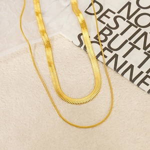 Close-up of double-layer gold snake chain necklace on minimalist aesthetic background